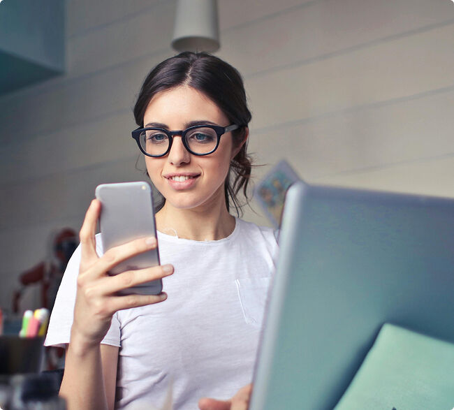 A smiling older woman wearing glasses talking with a healthcare professional across a clinic counter